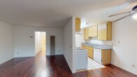 Located at 543 N Madison Ave in the Hancock Park-adjacent neighborhood of Los Angeles, this single-floor unit offers a practical and well-organized layout. The living area is a standout feature, showcasing rich, dark hardwood flooring that runs throughout the main living and dining spaces, complemented by bright white walls and a ceiling fan that enhances air circulation. Large windows fitted with vertical blinds allow natural light to fill the room, and a wall-unit air conditioner provides climate control. The open layout connects the living area to the kitchen, which is designed in a galley configuration. It features light wood cabinetry, granite-style laminate countertops, a gas range, dishwasher, refrigerator, and double sink — offering ample storage and counter space for everyday cooking. Light ceramic tile floors keep the kitchen area clean and easy to maintain. The bedroom is a comfortable, carpeted room with a generous window that brings in natural light, creating a calm and restful atmosphere. The bathroom is finished with light tile flooring, a single-sink vanity with storage, a toilet, and a shower-tub combination enclosed by sliding glass doors, with a high window providing ventilation and privacy. Overall, this unit delivers a functional and clean living environment in a well-connected Los Angeles location.