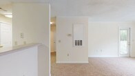 Located at 50 Maner Terr in Atlanta, Georgia, this single-floor unit offers a practical and comfortable layout designed for everyday living. The open living area is generously sized, finished with neutral-toned carpet and warm beige walls that create a bright, welcoming atmosphere. Large windows allow ample natural light to fill the space, with views of the surrounding greenery outside. A door provides direct access to an outdoor area, extending the living experience beyond the interior. The living space connects to the kitchen, which features rich wood-toned cabinetry, a white refrigerator, an electric range, and hard surface flooring that adds a clean contrast to the carpeted areas. A textured ceiling runs throughout, adding a classic residential character to each room. The bedroom is well-proportioned and carpeted, with a window that draws in natural light and includes crown molding for an added touch of detail. A standout feature is the spacious walk-in closet, equipped with multiple wire shelving units and hanging rods, offering excellent storage capacity. The bathroom is cleanly finished with wood-look flooring, a tiled tub-shower combination, and functional fixtures. Overall, the unit presents a functional and well-maintained living environment in a convenient Atlanta location.
