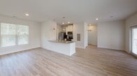 Located at 50 Cheryl Lane in Summerville, SC, this single-floor residence offers a clean, contemporary design with a thoughtful layout. The open-concept living and dining area is bathed in natural light from multiple windows and French doors that lead to a private balcony, creating a seamless indoor-outdoor connection. Light-toned hardwood-style flooring runs throughout the main living areas, adding warmth and continuity to the space.

The kitchen is well-appointed with white cabinetry, granite countertops, stainless steel appliances including a refrigerator, range, microwave, and dishwasher, along with a central island that doubles as a breakfast bar illuminated by pendant lighting. A decorative lattice wine rack adds a charming touch above the upper cabinets.

The bedrooms are carpeted for comfort and each features a ceiling fan, natural light from windows with blinds, and closet space. The bathrooms are finished with granite-topped vanities, white cabinetry, wood-look tile flooring, and tub-shower combinations with tile surrounds. A dedicated laundry area with an in-unit washer and overhead shelving adds everyday convenience. The overall aesthetic is bright, neutral, and move-in ready.