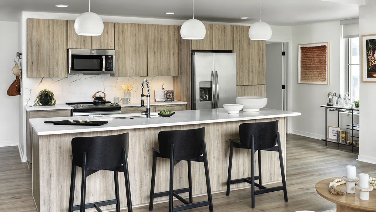 Cocina del apartamento con electrodomésticos de acero inoxidable, encimeras de cuarzo y pisos de madera. - Griffis LoDo