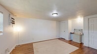 Located at 7703 Hare Ave in Jacksonville, FL, this single-floor unit offers a practical and efficient layout across its thoughtfully arranged rooms. The main living area features warm wood-look flooring, a textured ceiling, and a wall-mounted A/C unit, with a window that brings in natural light and a clean, neutral color palette that keeps the space feeling open and bright.

The kitchen is outfitted with white cabinetry, a coil-burner electric range, a full-size refrigerator, and a countertop sink — all finished in white for a cohesive, clean look. A utility-style hanging rack keeps cooking tools within easy reach. The kitchen flows directly into the dining area, which features light tile flooring, a compact fold-down table with two chairs, and a small wall-mounted shelving unit — making smart use of the available space.

The bathroom is finished with classic white subway tile surrounding the tub-shower combo, mosaic tile flooring, a white vanity with mirror, and all essential fixtures. Two closets provide convenient storage solutions. Throughout the unit, the consistent use of white walls and light finishes creates a cohesive, tidy ambiance well-suited to efficient, comfortable living.
