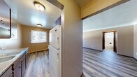 Located on Minnehaha Ave E in Saint Paul, MN, this one-bedroom, one-bathroom unit offers a practical and well-organized single-floor layout. Hardwood-style laminate flooring runs consistently throughout the space, providing a cohesive and easy-to-maintain surface in every room.

The living room is the largest area in the unit, featuring a textured ceiling, neutral warm-toned walls, and a wall-mounted air conditioning unit alongside baseboard heating. Large windows invite natural light and offer views of the surrounding residential neighborhood and mature trees. The open sightlines into the kitchen area create a connected, functional flow.

The kitchen is positioned adjacent to the living space and includes dark wood cabinetry overhead and a full-size refrigerator. A window above the kitchen area provides additional natural light. Baseboard heating is present here as well.

The bedroom is a well-proportioned private retreat with a ceiling fan, a window with exterior views, and a dedicated closet with a sliding door and hanging rod. Neutral wall tones and the same laminate flooring continue throughout.

The bathroom features full white tile surround on the tub-shower combo, a frosted glass block window, a dark wood vanity with an integrated sink, a medicine cabinet with mirror, and hardwood-style flooring. A hallway connects the main rooms, completing this efficiently designed unit.