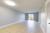 Located in Lauderhill, Florida, this 2-bedroom, 2-bathroom residence offers a well-organized single-floor layout designed for comfortable everyday living. Light-toned ceramic tile flooring runs consistently throughout the home, complementing the cool blue-grey walls and white trim found across most rooms.

The combined living and dining area forms the heart of the home, featuring a textured ceiling, ample wall space, and a sliding glass door that opens to a private outdoor area with textured stucco walls — ideal for enjoying the Florida climate. A separate dining room provides additional space for meals and entertaining.

The kitchen is equipped with modern stainless steel appliances, including a refrigerator, range, microwave, and dishwasher, all set against light wood-toned cabinetry and granite-style countertops. A window above the sink allows natural light to brighten the space.

Both bedrooms are well-proportioned, featuring the same consistent tile flooring, soft wall tones, and textured ceilings. The primary bedroom is notably spacious and includes direct access to its own bathroom. Each bedroom benefits from natural light through windows fitted with blinds.

The bathrooms stand out with stylish finishes, particularly the walk-in shower adorned with large-format wood-look tiles, a decorative mosaic accent border, and a pebble-tile shower floor — adding a refined touch to the overall design.