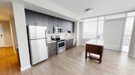 Located in Alexandria, Virginia, this contemporary two-bedroom, two-bathroom residence offers a well-designed single-floor layout with modern finishes and an abundance of natural light. The open-concept living and kitchen area is anchored by expansive floor-to-ceiling windows that flood the space with daylight and provide access to a private balcony, where sweeping elevated views of the surrounding cityscape can be enjoyed. The kitchen is outfitted with dark wood cabinetry, a subway tile backsplash, stainless steel appliances including a range, microwave, and dishwasher, and a central island that adds both workspace and versatility. Light wood-tone flooring runs throughout the main living areas, lending warmth and continuity to the open layout. Both bedrooms are carpeted for comfort and feature windows with city or building views. Closets provide dedicated storage in the bedrooms, with built-in rod and shelf systems. The two bathrooms are finished with large-format light tile flooring and sleek dark wood vanities with white countertops. The primary bathroom includes a glass-enclosed walk-in shower and a double-sink vanity, while the second bathroom features a soaking tub and shower combination. A hallway connects the living areas to the bedrooms, completing a thoughtfully planned and contemporary residence.