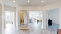 Located at 9 Hellers Lane in Jefferson, NJ, this thoughtfully designed single-floor residence offers a bright, open layout with two bedrooms and two full bathrooms. Light-toned hardwood-style flooring flows seamlessly throughout, complementing the clean white walls and recessed lighting that define the home's modern aesthetic. The entry hallway, accented by a full-length gold-framed mirror, leads into a spacious open living and dining area filled with natural light from oversized windows that frame outdoor views of the surrounding landscape. The kitchen is well-appointed with sleek gray shaker cabinets, quartz countertops, stainless steel appliances, and an island, making it as functional as it is stylish. The dining area features large windows and gallery wall space, creating an inviting atmosphere. The generously sized primary bedroom includes multiple closets and ample space for furnishings, while the second bedroom benefits from a bright window with scenic views. Both bathrooms are finished with light tile flooring and modern vanities — one featuring a walk-in glass shower and extended countertop, the other offering a clean, accessible design. Additional highlights include four closets, a hallway with smart storage, and a private patio for outdoor enjoyment.