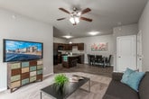 This single-floor residence offers a thoughtfully designed layout that balances functionality and comfort throughout its well-defined living spaces. Neutral gray walls and consistent finishes create a cohesive aesthetic from room to room.

The kitchen is a functional centerpiece, featuring dark espresso cabinetry, granite-style laminate countertops, and a full suite of black appliances including a range, microwave, dishwasher, and refrigerator. A kitchen island with bar seating provides additional prep and dining space, complemented by an adjacent dining area with wood-look plank flooring that continues throughout the kitchen zone.

The living room is carpeted and generously proportioned, with a ceiling fan overhead and a sliding glass door that opens to a private balcony, allowing natural light to fill the space. The layout transitions smoothly into a flexible den or office area, also carpeted and featuring a window with outdoor views.

Bedrooms are carpeted and include closet storage; one features a spacious walk-in closet outfitted with wire shelving and hanging rods. The bathroom is equipped with a full tub and shower combination, a vanity with granite-style countertops, dark cabinetry, and durable tile flooring in a warm stone pattern.