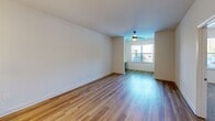 Located at 1000 Lassen Dr in Knightdale, NC, this well-designed one-bedroom, one-bathroom residence offers a comfortable and modern living experience across a single floor. The open-concept layout seamlessly connects the kitchen and living room, both finished with warm-toned hardwood-style flooring that runs throughout the main areas. The kitchen is a standout feature, equipped with stainless steel appliances including a range, microwave, and refrigerator, complemented by a stainless steel range hood, white shaker-style cabinetry, and a peninsula with a white quartz countertop and pendant lighting overhead — ideal for both cooking and casual dining. The living area is bright and airy, benefiting from natural light through a large window and a ceiling fan for year-round comfort. The bedroom is carpeted for warmth and comfort, outfitted with its own ceiling fan, and provides direct access to both the bathroom and a generously sized walk-in closet with extensive wire shelving for ample storage. The bathroom features a full soaking tub with a curved shower rod, hardwood-style flooring, and a clean, bright aesthetic throughout. The overall ambiance is modern and move-in ready.