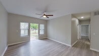 Located at 28 Lynn Batts Ln in San Antonio, Texas, this single-story home offers a clean, modern interior with a cohesive neutral color palette throughout. The living areas feature light wood-style flooring and ceiling fans, creating a comfortable and airy atmosphere. Large windows and sliding glass doors allow natural light to fill the space while providing views of the surrounding greenery and outdoor yard area.

The kitchen is designed for functionality, featuring a galley-style layout with gray shaker cabinetry, white countertops, a undermount sink, and stainless steel appliances including a range, microwave, and refrigerator. Wood-style flooring continues seamlessly from the kitchen into the main living areas.

The bedrooms are well-proportioned, each equipped with ceiling fans and windows with blinds that invite natural light. The bathroom is thoughtfully appointed with gray vanity cabinetry, white countertops, a tiled tub-shower combination with a decorative tile border accent, stone-look tile flooring, and overhead cabinetry for additional storage.

A dedicated laundry area with wire shelving and utility hookups adds everyday convenience. The exterior features a yard with mature trees and a patio, extending the living space outdoors. This home presents a well-maintained, move-in-ready environment in a residential San Antonio neighborhood.