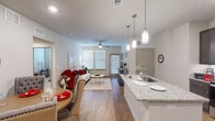 Located at 3640 Harmony Commons Drive in Spring, TX, this thoughtfully designed 2-bedroom, 2-bathroom residence offers a comfortable and functional single-floor layout. The open-concept living area seamlessly connects the kitchen, dining, and living spaces, creating an inviting atmosphere filled with natural light from large windows fitted with blinds and accented by ceiling fans overhead.

The kitchen is a standout feature, boasting dark espresso cabinetry, granite countertops, stainless steel appliances, and a peninsula island illuminated by stylish pendant lighting — ideal for both cooking and casual dining.

The living room offers a warm, relaxed ambiance with wood-style flooring that extends throughout the main areas. Each bedroom is carpeted for added comfort; the primary bedroom is a well-sized retreat with ample room for a full furniture arrangement. Both bedrooms are served by dedicated closets with built-in shelving and hanging rods for organized storage.

The two bathrooms are finished with granite-topped dark vanities and wood-style flooring. One bathroom features a tub-shower combination, while the primary bath includes direct access to a walk-in closet. A connecting hallway ties all areas of the home together cohesively, completing this well-rounded and move-in-ready residence.