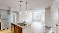 Located at 1100 South Boulevard in Charlotte's vibrant South End neighborhood, this well-appointed 2-bedroom, 2-bathroom residence offers a thoughtfully designed single-level layout. The open-concept living area flows seamlessly from the kitchen through the dining space and into a bright living room, all finished with light hardwood-style flooring and ceiling fans. Large windows allow natural light to fill the space throughout.

The kitchen is a standout, featuring dark espresso cabinetry, a granite-topped island with a double stainless steel sink, white subway tile backsplash, and a full suite of stainless steel appliances including a refrigerator, range, and built-in microwave.

Both bathrooms mirror the kitchen's design aesthetic with dark vanity cabinetry, granite countertops, and wood-look tile flooring. One bathroom includes a soaking tub, while the other features a walk-in shower.

The bedrooms are carpeted for comfort and each includes a ceiling fan and natural light from well-placed windows. The primary bedroom is generously sized and features a walk-in closet with wire shelving for ample storage. A dedicated laundry area and two closets round out the functional layout of this modern Charlotte residence.