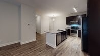 Located at 1512 Kippford Way in Myrtle Beach, South Carolina, this single-floor residence offers a well-designed layout with a cohesive blend of modern finishes and functional living spaces. The floor plan, visible in the 3D overview, reveals an open-concept arrangement connecting the kitchen, dining, and living areas with a logical flow into the private bedrooms.

The kitchen is a standout feature, equipped with rich dark cabinetry, granite countertops, and a full suite of stainless steel appliances including an electric range, built-in microwave, and dishwasher. A peninsula with a granite surface and undermount sink serves as both a prep area and a casual gathering point, illuminated by a pendant light overhead.

The living area extends from the kitchen and features dark wood-look flooring, a ceiling fan, and access to a door leading outside, allowing for natural light. The bedrooms are carpeted and each includes a closet, providing comfortable and quiet retreats from the main living spaces.

The bathrooms are consistent in design, each featuring wood-look tile flooring, a tub-shower combination with brushed nickel fixtures, a dark vanity with granite countertops, and a large mirror. The neutral gray tones throughout the unit create a clean, modern aesthetic suited for a variety of styles.