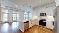 Located at 2925 Buford Dr in Buford, Georgia, this single-floor residence showcases a thoughtfully designed open layout with contemporary finishes. The kitchen serves as a central highlight, featuring white shaker-style cabinetry, light quartz countertops, and a geometric hexagonal tile backsplash. Stainless steel appliances, including a range, over-the-range microwave, and dishwasher, are integrated seamlessly into the design. A peninsula with an undermount sink provides additional workspace and casual seating potential. Pendant lighting and recessed fixtures illuminate the space, while multiple windows invite abundant natural light and connect the kitchen to the adjoining living area. Warm hardwood-style flooring flows throughout the main living spaces.

The bedrooms are carpeted and well-lit, with large windows fitted with horizontal blinds. The primary bedroom benefits from corner window placement, enhancing brightness and openness. Each bedroom is accompanied by a walk-in closet outfitted with wire shelving systems for practical organization.

The bathrooms feature wood-look vinyl flooring, white vanity cabinetry with quartz countertops, framed mirrors, and brushed nickel hardware. One bathroom includes a soaking tub with full tile surround, while another offers a walk-in shower, providing versatile options throughout the home.