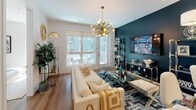 This thoughtfully designed single-floor residence showcases a bold, eclectic interior style that seamlessly blends contemporary finishes with vibrant personality. Warm hardwood-style flooring flows throughout the space, unifying each room cohesively.

The living area makes an immediate impression with a striking teal accent wall, a statement Sputnik chandelier in brushed gold, and large windows with sliding glass door access to a private balcony, filling the room with natural light. The galley-style kitchen is outfitted with flat-front wood cabinetry, stainless steel appliances including a gas range and refrigerator, white quartz countertops, a deep undermount sink, and a tile backsplash — all anchored by a bold navy accent wall with a decorative round mirror.

The bedroom is a serene retreat centered around a dark charcoal accent wall adorned with organic wall art, complemented by a ceiling fan, a walk-in closet, and a window that brings in additional natural light. The en-suite bathroom features large-format marble-look tile, a frameless glass walk-in shower, and clean, minimalist finishes throughout.

The welcoming entryway is appointed with a solid wood door, sunburst mirror, and light-toned flooring, setting the tone for the stylish interior within.