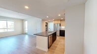 North Grove B2B is a thoughtfully designed 2-bedroom, 2-bathroom apartment spanning 950 square feet on a single floor in Riverside, California. The open-concept kitchen and living area serves as the heart of the unit, featuring a sleek kitchen island with a dark quartz countertop and integrated sink, two-tone cabinetry with white upper and dark lower cabinets, a subway tile backsplash, and stainless steel appliances including a refrigerator, range, and built-in microwave. Recessed lighting and light wood-style flooring enhance the modern, airy ambiance throughout the shared living spaces. The primary bedroom measures 130 square feet and includes a dedicated closet, while the secondary bedroom offers plush carpeting and a large window with views of the surrounding community. Each bedroom is served by its own full bathroom, both finished with wood-look flooring, a tiled tub-shower combination, and clean white walls accented by brushed nickel fixtures. One bathroom includes a dark vanity with an undermount sink and a large mirror. Two closets and a hallway provide additional storage. The unit offers outdoor views of the well-maintained North Grove community, complete with covered parking structures and mountain vistas under sunny Southern California skies.