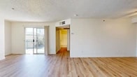 Located at 2736 W Lincoln Ave in Anaheim, CA, this one-bedroom, one-bathroom unit offers a functional and well-appointed single-floor layout. Light wood plank flooring flows consistently throughout the space, creating a clean, cohesive aesthetic complemented by crisp white walls and textured ceilings.

The combined kitchen and living area forms the heart of the unit. The kitchen features warm wood cabinetry, granite countertops, a peninsula with a breakfast bar overhang, and a white range with an overhead vent. A sliding glass door in the living area opens to a private balcony, overlooking a courtyard with palm trees and open sky — ideal for enjoying Southern California's climate.

The bedroom is generously proportioned, benefiting from a dedicated window that draws in natural light and contributes to an airy feel. The clean, neutral walls and wood flooring carry through here, providing a calm and versatile space.

The hallway connects the main living areas to the full bathroom, which includes a shower-tub combination, a wood-framed vanity with granite countertops, and consistent wood-tone flooring. A dedicated entrance and hallway complete the layout, providing a clear and organized transition into the unit. The overall design is practical, light-filled, and move-in ready.
