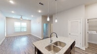 This single-story residence offers two bedrooms and two full bathrooms within a thoughtfully designed open-concept layout. The kitchen serves as a central highlight, showcasing rich dark espresso cabinetry with sleek hardware, light granite countertops, a central island with a double stainless steel sink and pendant lighting overhead, and a full suite of stainless steel appliances. Recessed lighting and wood-look plank flooring extend throughout the main living areas, creating a cohesive and modern aesthetic.

The living area is spacious and bright, benefiting from natural light through large windows and a ceiling fan overhead. Both bedrooms feature plush carpeting, ceiling fans, and windows that invite natural light. The primary bathroom is well-appointed with a dual-sink vanity topped with granite, dark cabinetry, tile flooring, and a walk-in tiled shower. The secondary bathroom mirrors the design with granite countertops, dark cabinetry, and a full tub-shower combination. Neutral tones throughout lend the space a clean, contemporary feel.