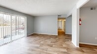 This single-story, 3-bedroom, 2-bathroom home offers a practical and comfortable layout designed to maximize everyday living. The living room is a bright, open space featuring warm wood-look luxury vinyl plank flooring, soft gray walls, a textured ceiling, and a sliding glass door that invites natural light from outside. A dedicated dining room flows naturally alongside the kitchen, which stands out with its galley-style design, white shaker cabinetry, granite-look countertops, a stainless steel sink, and black appliances — all set over matching LVP flooring. The three bedrooms provide flexible living options; the primary bedroom is generously sized, while the secondary bedrooms offer a mix of LVP and plush carpet flooring, all sharing the same neutral gray palette and textured ceilings. Five closets are distributed throughout the home, ensuring exceptional storage capacity. The two bathrooms each feature a tub-shower combo with white tile surrounds and brushed nickel fixtures; one bathroom showcases LVP flooring and a white vanity. A central hallway connects the private sleeping quarters to the main living areas, completing this efficiently organized and move-in-ready home.