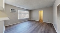 Located at 4640 Arden Way in El Monte, California, this single-floor unit offers a thoughtfully laid-out living space with modern updates throughout. The open-concept living area features warm-toned laminate hardwood flooring, neutral gray walls, and a textured ceiling. A wall-mounted A/C unit and a tall vertical heater ensure year-round comfort, while a large window with vertical blinds fills the room with natural light.

The kitchen is efficiently designed with white shaker-style cabinetry, a decorative tile backsplash, and a clean white countertop with a peninsula that opens to the living area. It is equipped with a black gas range, over-the-range microwave, and a stainless steel refrigerator, making it a fully functional cooking space.

The bathroom is clean and modern, featuring a white vanity with a single-basin sink, a large mirror, and a glass-enclosed shower. A window above the shower area brings in natural light while maintaining privacy. The hallway connects the main living space to the bathroom, providing a logical and efficient flow throughout the unit. Overall, the space presents a clean, move-in-ready aesthetic with practical finishes suited for comfortable everyday living.