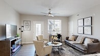 This single-floor residence offers a thoughtfully designed open-concept layout that seamlessly connects the main living areas. The living room serves as the heart of the home, featuring light wood-style flooring, neutral-toned walls, a ceiling fan, and natural light streaming through large windows with views of the surrounding community. A dedicated workspace area is tucked neatly into the living space, adding functional versatility.

The kitchen is well-equipped with rich dark cabinetry, granite-style countertops, and black appliances including a refrigerator, range, and dishwasher. A spacious island with pendant lighting and bar seating provides both additional prep space and a casual dining option. An adjacent dining area features hardwood-style flooring and an elegant chandelier overhead, creating a refined setting for meals.

The bedroom is a calm retreat with plush carpet flooring and clean, neutral walls. It connects to a generously sized walk-in closet outfitted with wire shelving and hanging rods. The bathroom is finished with dark wood cabinetry, granite countertops, a single sink vanity, modern lighting, and an adjacent linen storage area with wire shelving. Throughout the space, consistent neutral tones, modern finishes, and natural light create a cohesive and welcoming ambiance.