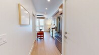 Located at 801 E Whiting St in the heart of downtown Tampa, FL, this thoughtfully designed studio makes exceptional use of its single-floor layout. Light wood flooring flows throughout, complementing a clean, contemporary palette of whites and warm neutrals that lend the space a bright, airy feel.

The main living area centers around a built-in Murphy bed with warm wood wall paneling, seamlessly doubling as a living and sleeping space. A cozy dining nook with a round wooden table adds functional character. Floor-to-ceiling glass doors open onto a private balcony, flooding the room with natural light and offering impressive views of the Tampa skyline — a standout feature of this space.

The kitchen is efficiently appointed with stainless steel appliances, a gas range, white quartz countertops, dual-tone cabinetry in white and wood-grain finishes, and a geometric light-blue tile backsplash with under-cabinet LED lighting. A stacked washer and dryer unit is also included.

The bathroom showcases refined finishes, including marble-look hexagonal floor tiles, a frameless glass-enclosed walk-in shower with white subway tile surround, and brushed nickel fixtures throughout. The overall design is modern, functional, and polished — ideal for urban living in one of Tampa's most vibrant neighborhoods.
