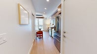 Located at 801 E Whiting St in the heart of downtown Tampa, FL, this thoughtfully designed studio makes exceptional use of its single-floor layout. Light wood flooring flows throughout, complementing a clean, contemporary palette of whites and warm neutrals that lend the space a bright, airy feel.

The main living area centers around a built-in Murphy bed with warm wood wall paneling, seamlessly doubling as a living and sleeping space. A cozy dining nook with a round wooden table adds functional character. Floor-to-ceiling glass doors open onto a private balcony, flooding the room with natural light and offering impressive views of the Tampa skyline — a standout feature of this space.

The kitchen is efficiently appointed with stainless steel appliances, a gas range, white quartz countertops, dual-tone cabinetry in white and wood-grain finishes, and a geometric light-blue tile backsplash with under-cabinet LED lighting. A stacked washer and dryer unit is also included.

The bathroom showcases refined finishes, including marble-look hexagonal floor tiles, a frameless glass-enclosed walk-in shower with white subway tile surround, and brushed nickel fixtures throughout. The overall design is modern, functional, and polished — ideal for urban living in one of Tampa's most vibrant neighborhoods.