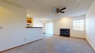 Located at 2801 N Rock Rd in Wichita, Kansas, this single-floor residence offers a well-organized and functional layout throughout. The open-concept living and dining area is a central highlight, featuring plush carpeting, a ceiling fan with light fixture, and a wood-framed fireplace with a tile surround and glass doors that serves as a striking focal point. A sliding glass door with vertical blinds allows natural light to fill the space and provides outdoor access. The living area transitions seamlessly between hardwood-style flooring and carpet, adding visual interest to the layout. The kitchen is efficiently designed with warm wood cabinetry, white appliances including a refrigerator, microwave, and dishwasher, and a pass-through breakfast bar that connects to the living space. The bedroom is generously sized with soft carpeting, a ceiling fan, a window with blinds for natural light, and a full-width mirrored sliding closet that enhances the sense of space. The bathroom is clean and practical, featuring a wood-toned vanity with a white countertop, a full tub-and-shower combination, and wood-look vinyl flooring. Textured ceilings are consistent throughout, lending the home a classic character.