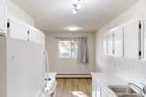 Located in Red Deer, Alberta, this well-laid-out 2-bedroom, 2-bathroom unit offers a comfortable and functional single-level floor plan. Light-toned hardwood flooring runs throughout the main living areas, contributing to a clean and bright aesthetic. The spacious combined living and dining area is a highlight of the unit, featuring multiple windows that invite generous natural light and views of the surrounding greenery. Baseboard heating is present throughout, ensuring year-round comfort.

The galley-style kitchen is efficiently designed with white cabinetry lining both sides, a double stainless steel sink, white appliances including a refrigerator and electric range, a tile backsplash, and a window overlooking the outdoors. Track lighting overhead provides ample illumination for food preparation.

The primary bedroom is generously sized, with a large window framing outdoor views and a closet for storage. The second bedroom is bright and functional, also with hardwood flooring. Four closets total are distributed throughout the unit, offering practical storage solutions. Both bathrooms include a full tub-shower combination with tiled surrounds. A hallway connects the rooms in a logical flow, completing this tidy and livable layout.