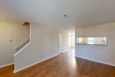 Located at 912 Peach Hill Ln in Chesterfield, Missouri, this two-story home offers a well-organized layout spread across two floors. The main level features an open-concept living and dining area finished with rich wood-look flooring and neutral beige walls that create a warm, inviting atmosphere. A staircase leads to the upper level, and a pass-through window connects the living area to the kitchen, enhancing the sense of openness. The kitchen is equipped with white cabinetry featuring wood-tone accents, a full suite of appliances including a range, microwave, and refrigerator, and a breakfast bar counter. Natural light flows in through multiple windows, and the dining area benefits from a charming chandelier and a glass-paneled door that opens to the outdoors. Upstairs, the generously sized primary bedroom features plush carpeting, a ceiling fan, and a walk-in closet outfitted with wire shelving for ample storage. Two bathrooms serve the home, one of which includes a full tub/shower combination with a bright window. The overall design is clean and functional, with consistent neutral tones and durable finishes throughout, making this Chesterfield home a practical and comfortable residence.