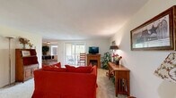 Located at 600 Bennett Way in Newmarket, NH, this thoughtfully laid-out single-floor residence offers a practical and comfortable living environment across a well-utilized footprint. The open-concept living area is anchored by plush carpeting and features a fireplace, creating a warm and inviting atmosphere. A sliding glass door leads directly to an outdoor patio, allowing natural light to fill the space and providing easy access to the outdoors. The living room flows seamlessly into the dining area, where warm hardwood flooring, a bright window, and a ceiling light fixture lend a clean, welcoming feel. The kitchen is a standout feature, showcasing rich dark wood cabinetry, stainless steel appliances including a refrigerator, microwave, and range, and a peninsula with a light stone countertop and undermount sink — ideal for both cooking and casual dining. The bedroom offers a cozy carpeted retreat with warm neutral tones and ample wall space. A dedicated office provides a quiet area suited for work or study. The bathroom is finished with wood flooring, a full tub-shower combination, and a vanity with cabinet storage. Throughout, the residence maintains a consistent, neutral palette that creates a calm and cohesive living environment.
