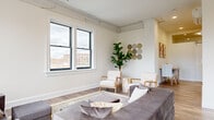 Located on the third floor at 174 E Long St in downtown Columbus, Ohio, this one-bedroom, one-bathroom unit offers a well-designed layout across a single floor. Hardwood-style flooring runs throughout, lending a cohesive and modern aesthetic to the entire space.

The living area is bright and open, featuring large black-framed windows that frame views of the Columbus skyline and allow generous natural light to fill the room. Exposed structural details along the ceiling add a subtle industrial character that complements the clean, white walls.

The kitchen is efficiently arranged and equipped with a full suite of stainless steel appliances, including a refrigerator, range, built-in microwave, and dishwasher. White cabinetry and light countertops keep the space feeling fresh and functional, with a window providing additional natural light.

A hallway fitted with sleek white barn doors leads to the cozy bedroom, which is an intimate and well-proportioned retreat with track lighting and warm neutral tones. The bathroom is clean and contemporary, featuring a gray vanity with a white countertop, an illuminated mirror, and a shower-tub combination. A compact dining nook tucked within the hallway area adds a practical and charming touch to the overall layout.