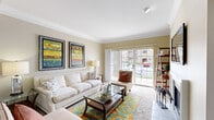 Located in O'Fallon, Missouri, this single-floor, 3-bedroom, 2-bathroom home offers a thoughtfully designed layout across a comfortable footprint. The living room serves as the heart of the home, featuring crown molding, a classic fireplace, and large sliding glass doors that invite abundant natural light and provide views of the outdoors. The adjacent dining area continues the warm, neutral color palette, with rich hardwood-style flooring, a tray ceiling with crown molding detail, and a pendant light fixture that anchors the space. The galley-style kitchen is efficiently arranged with ample light wood cabinetry, dark granite-style countertops, and black appliances, including a refrigerator, range, and dishwasher. A doorway from the kitchen provides convenient access to the in-unit laundry room. The spacious primary bedroom features plush carpeting, a large window with outdoor views, and generous room for furnishings. The additional bedrooms are similarly bright and carpeted, each with windows overlooking the surroundings. The bathrooms include warm wood cabinetry and hardwood-style flooring. A dedicated closet and laundry room round out this functional and inviting home.