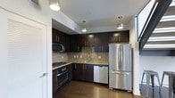 This two-floor residence offers a thoughtfully designed living space with modern finishes and functional layouts across both levels. The kitchen stands out as a highlight of the home, showcasing rich dark espresso cabinetry that extends to the ceiling, providing ample storage. Granite countertops add a touch of elegance, while a classic tile backsplash ties the design together seamlessly. The kitchen is fully equipped with stainless steel appliances, including a French door refrigerator, a built-in dishwasher, a gas range with oven, and an over-the-range microwave. Pendant lighting fixtures hang above the workspace, casting warm, focused light over the countertops and enhancing the kitchen's contemporary aesthetic. Rich hardwood flooring runs throughout, adding warmth and continuity to the space. The overall ambiance of the residence is modern and inviting, with clean lines and a neutral color palette that allows for versatile interior styling. Spread across two floors, the layout offers a natural separation between living and private spaces, making it well-suited for both everyday living and entertaining.