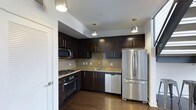 This two-floor residence offers a thoughtfully designed living space with modern finishes and functional layouts across both levels. The kitchen stands out as a highlight of the home, showcasing rich dark espresso cabinetry that extends to the ceiling, providing ample storage. Granite countertops add a touch of elegance, while a classic tile backsplash ties the design together seamlessly. The kitchen is fully equipped with stainless steel appliances, including a French door refrigerator, a built-in dishwasher, a gas range with oven, and an over-the-range microwave. Pendant lighting fixtures hang above the workspace, casting warm, focused light over the countertops and enhancing the kitchen's contemporary aesthetic. Rich hardwood flooring runs throughout, adding warmth and continuity to the space. The overall ambiance of the residence is modern and inviting, with clean lines and a neutral color palette that allows for versatile interior styling. Spread across two floors, the layout offers a natural separation between living and private spaces, making it well-suited for both everyday living and entertaining.