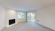 Located in Redmond, WA, this one-bedroom, one-bathroom residence offers a well-designed single-floor layout that balances comfort and functionality. The open-concept living and kitchen area forms the heart of the home, where a bright, carpeted living room anchors the space with a classic white-mantled fireplace and large windows that frame tranquil, tree-lined views. A sliding glass door leads directly to a private balcony, extending the living space outdoors and further connecting the interior to its natural surroundings. The kitchen is thoughtfully appointed with white cabinetry, light countertops, a peninsula island with a stainless steel sink and modern pull-down faucet, recessed lighting, and light wood-look flooring — offering a clean, contemporary aesthetic. An arched passageway adds an architectural touch between the kitchen and hallway. The bedroom is a comfortable, carpeted retreat with natural light filtering in through a window overlooking greenery, and connects conveniently to the hallway. The bathroom features a full tub-shower combination with white tile surround and brushed nickel fixtures, maintaining the home's clean and neutral palette throughout. Baseboard heating and recessed lighting complete the practical, well-finished interior.