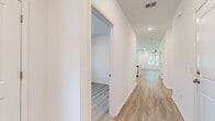 Located at 129 Mainland Lakes Dr in Bluffton, SC, this single-story home offers four bedrooms, two bathrooms, and a thoughtfully designed layout across a comfortable footprint. Light wood-look flooring runs consistently throughout, lending a cohesive, clean aesthetic to every room.

The kitchen serves as a central hub of the home, featuring white shaker cabinetry, stainless steel appliances, a tile backsplash, and a granite-topped island with a built-in sink — ideal for both meal preparation and casual dining. Recessed lighting illuminates the space, which flows naturally into the adjacent living area.

The primary bedroom is generously sized and benefits from two windows overlooking greenery, a ceiling fan, and recessed lighting. It connects to a private bathroom equipped with a dual-sink vanity, white countertops, and a glass-enclosed shower. A dedicated walk-in closet with wire shelving provides practical storage.

The remaining three bedrooms are bright and well-proportioned, each finished with the same light flooring and neutral white walls. One room features a sliding glass door opening directly to the outdoors. A dedicated laundry room includes a full-size washer and dryer with overhead cabinetry and additional wire shelving.