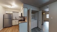 This single-floor unit offers a thoughtfully updated interior with consistent wood-look flooring and textured ceilings throughout. The kitchen serves as a standout feature, showcasing white shaker-style cabinetry, a striking white subway tile backsplash, stainless steel appliances including a refrigerator, range with microwave, and a stainless undermount sink — all finished with dark countertops for contrast. Track lighting illuminates the space effectively. Conveniently adjacent to the kitchen is a dedicated laundry closet housing a full-sized washer and dryer. The bedrooms are well-sized, each equipped with ceiling fans and window blinds that allow for natural light. The flooring transitions from lighter tones in the kitchen and living areas to a deeper wood-look finish in the bedrooms, adding visual warmth. Two bathrooms are present: one features a floating wood-toned vanity with a white basin sink, framed mirror, and a tub-shower combination, while the second offers a similar tub-shower layout. The living area is open and welcoming, with a paneled entry door and ample wall space. Overall, the unit presents a clean, modern aesthetic with practical, functional updates throughout.