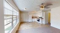 Located at 3456 New Hartford Rd in Owensboro, Kentucky, this single-floor home offers a practical and comfortable layout with a warm, neutral palette throughout. The open-concept living and dining area flows seamlessly into the kitchen, with a transition from soft carpeting to tile flooring that defines each functional zone. A ceiling fan with a light fixture overhead and a large multi-pane window along one wall flood the living space with natural light and offer views of the surrounding neighborhood.

The kitchen is well-appointed with white cabinetry extending to the ceiling, providing generous storage. A full suite of white appliances includes a refrigerator, electric range, and dishwasher, all complemented by a warm-toned countertop and a track lighting fixture above. The L-shaped layout makes efficient use of the space.

The bedrooms feature plush carpet flooring, ceiling fan light fixtures, and bright white walls. At least one bedroom includes a reach-in closet with a hanging rod, offering ample storage. The bathroom is clean and functional, featuring a full tub and shower combination with white tile surround and chrome fixtures.

Throughout the home, textured ceilings, white trim, and neutral wall tones create a cohesive and move-in-ready aesthetic.