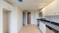 Located at 120 State St in the heart of Portland, Maine, this single-floor unit offers a clean, modern aesthetic throughout. The open-concept layout connects the kitchen and living area seamlessly, creating an efficient and functional flow. The kitchen is outfitted with stainless steel appliances, including an electric range and over-the-range microwave, complemented by white cabinetry and dark granite countertops that add a refined contrast. The living area benefits from a large window that frames views of Portland's charming streetscape, filling the space with natural light, while a wall-mounted mini-split unit ensures year-round comfort. Neutral-toned carpeting runs throughout the main living and sleeping areas, lending a warm, cohesive feel. The bedroom features a built-in storage nook with upper cabinetry, maximizing organization within a compact footprint. The bathroom is thoughtfully designed with a granite-topped vanity, gray cabinetry with ample drawer and cabinet storage, a framed mirror, and clean tile flooring. The unit's crisp white walls and understated finishes create a bright, move-in-ready environment well-suited for urban living in downtown Portland.