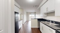This one-bedroom, one-bathroom unit at 5501 Prefontaine Ave in Regina, Saskatchewan, offers a well-designed layout that makes efficient use of its compact footprint. The kitchen is a standout feature, equipped with white cabinetry, dark granite-style countertops, black appliances including a refrigerator, electric range, and built-in microwave, plus a peninsula that provides additional prep space and separates the kitchen from the rest of the living area. Rich dark hardwood-style flooring runs throughout the main living spaces, adding warmth and visual continuity. The living room opens directly to a private balcony through sliding glass doors, offering views of the surrounding Regina neighbourhood and green space below. A wall-mounted mini-split air conditioning unit ensures year-round comfort, complemented by baseboard heating. The bedroom is carpeted for comfort, featuring a sliding closet and a large window that fills the room with natural light while overlooking the cityscape. The bathroom includes a full soaker tub and shower combination with clean white finishes. A hallway connects the rooms efficiently, completing this practical and modern urban unit.