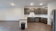 Located at 404 Gallop Ln in Charlotte, NC, this single-floor residence offers a clean, contemporary design throughout. Rich, dark hardwood-style flooring runs consistently across the living areas and bedrooms, providing a warm and cohesive aesthetic. The open-concept kitchen is a standout feature, equipped with stainless steel appliances including a range, over-the-range microwave, dishwasher, and refrigerator. Dark espresso-toned cabinetry with sleek hardware contrasts beautifully against light granite countertops, and a peninsula island adds additional prep and dining space. The living area is bright and open, benefiting from recessed lighting overhead. Bedrooms are well-proportioned, with large windows dressed in blinds that allow for natural light and outdoor views. One bedroom includes access to a walk-in closet with built-in shelving, offering practical storage solutions. The bathroom features a full soaking tub and shower combination with a tiled surround and brushed nickel fixtures, lending a clean and polished finish. Neutral wall tones throughout the home create a versatile backdrop, making the space easy to personalize. The overall ambiance is modern, functional, and move-in ready.