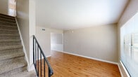 Located at 1401 19th Ave SE in Decatur, Alabama, this two-story home offers a straightforward and functional layout spread across two levels connected by a carpeted staircase with a black metal railing. The main level features warm hardwood-style flooring throughout the living area, which is open and well-lit with neutral wall tones and clean white trim. A compact, efficiently designed kitchen includes white cabinetry, laminate countertops, a double-basin sink, a white coil-top range, and a dishwasher, offering ample storage within its U-shaped configuration. A half bathroom with a vanity, mirror, and wood-style flooring is also found on this level. Upstairs, the hardwood-style flooring continues into a spacious landing area, while the bedrooms transition to plush carpet. One bedroom features a ceiling fan, a window with natural light, and generous proportions. Another bedroom includes a closet with a hanging rod and direct hallway access. The full bathroom on the upper level is finished in white with tile wainscoting, a single-sink vanity with a large mirror, and a bathtub/shower combination with a window above for natural light. Throughout, the home maintains a clean, neutral palette suited for a variety of furnishing styles.