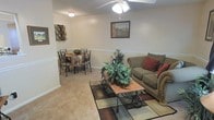 Located at 1815 Rosemont Dr in Greenville, NC, this single-floor home offers a welcoming and functional layout designed for comfortable everyday living. The open-concept living and dining area serves as the heart of the home, combining both spaces in a seamless flow that encourages easy interaction and entertaining. The living area features plush carpeting underfoot, providing warmth and comfort, while a ceiling fan overhead ensures year-round climate comfort. A decorative chair rail runs along the wall, adding a classic architectural detail that lends character to the space. The dining area is neatly defined within the same open footprint, offering an intimate setting for meals. Neutral wall tones throughout create a calm, versatile backdrop that complements a variety of décor styles. The overall ambiance of the home is cozy and approachable, with a traditional aesthetic that feels both lived-in and well-maintained. The single-floor layout provides convenient, step-free accessibility throughout the home, making it practical and easy to navigate. This property presents a straightforward, comfortable living environment in a residential Greenville neighborhood.
