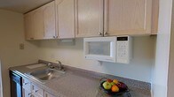 Located at 303 W State Street in Doylestown, Pennsylvania, this single-floor space offers a practical and well-appointed layout in one of Bucks County's most vibrant borough centers. The kitchen is a standout feature, showcasing light wood cabinetry that extends to the upper walls, providing generous storage throughout. The countertops feature a speckled granite-style surface that offers both durability and visual appeal. A built-in microwave is conveniently mounted beneath the upper cabinets, maximizing counter space and contributing to a clean, streamlined aesthetic. A stainless steel sink with a chrome faucet is positioned along the counter, completing the kitchen's functional design. The neutral color palette throughout the space — from the cabinet finishes to the wall tones — creates a warm and understated ambiance that is easy to personalize. The single-floor layout ensures seamless accessibility and ease of movement throughout the space. Situated in downtown Doylestown, the location provides convenient access to local shops, dining, cultural attractions, and public transportation, making it an ideally positioned space within this historic and walkable community.