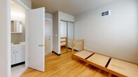 Located at 4754 18th Ave NE in Seattle's University District, this efficient single-bedroom unit on the third floor offers a well-organized, functional layout designed for comfortable solo living. The bedroom serves as the heart of the unit, featuring warm hardwood flooring that extends throughout the space, neutral gray walls, and two windows fitted with blinds that allow for controlled natural light. A built-in wooden desk and chair are positioned beneath the windows, providing a dedicated workspace. A mirrored sliding-door closet offers practical storage while adding a sense of depth to the room. A compact kitchenette area with a mini-refrigerator and countertop is tucked neatly into a corner of the main room, maximizing the use of available space. The private bathroom includes a clean, all-white walk-in shower stall. Overhead lighting and ceiling-mounted ventilation are present throughout. The unit's entry door features a secure double-lock system, and the overall design reflects a clean, minimalist aesthetic well-suited for academic living in close proximity to the University of Washington campus.