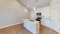 Located at 200 W Edge Way in Lynchburg, Virginia, this well-appointed single-floor residence offers a thoughtfully designed layout that balances open living spaces with comfortable private areas. The kitchen serves as a central highlight, showcasing white shaker cabinetry, a striking tile backsplash, stainless steel appliances, and a large center island with a quartz countertop and undermount sink. Pendant lighting and soaring vaulted ceilings lend the kitchen an airy, modern feel, while hardwood-style flooring extends throughout the main living areas. A spacious living area features vaulted ceilings, a ceiling fan, and French doors that invite natural light and provide outdoor access. The bedrooms are carpeted for warmth and comfort, each equipped with ceiling fans and generous windows that brighten the rooms. One bedroom includes a walk-in closet for added storage. The bathrooms are finished with tile flooring, white vanity cabinetry, and tub-shower combinations. A dedicated laundry room houses a full-size washer and dryer with overhead shelving for storage. Throughout the home, neutral tones, clean lines, and consistent finishes create a cohesive and inviting atmosphere suited for everyday living.