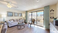 Located at 6250 N 19th Ave in Phoenix, Arizona, this one-bedroom, one-bathroom residence offers a thoughtfully designed single-level layout with wood-style flooring that flows seamlessly throughout the home. The combined kitchen and living area forms the heart of the space, where a bright, open-concept design encourages easy movement between rooms. The kitchen features rich, warm-toned cabinetry, granite-style countertops, a pass-through bar counter, and full appliances including a range and refrigerator, with a skylight overhead that enhances natural illumination. The living room is filled with natural light and opens directly onto a private balcony through large sliding glass doors, offering outdoor views and an inviting indoor-outdoor connection. The bedroom is a comfortable retreat, complete with a closet, natural light from a window, and a textured ceiling. The bathroom includes grab bars, a walk-in shower with a glass enclosure, a vanity with stone-style countertops, and wood-style flooring. A hallway connects the rooms efficiently, rounding out this compact yet functional floor plan. The textured ceilings and warm, neutral wall tones lend a consistent, welcoming ambiance throughout.