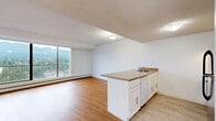 Located on Marine Drive in North Vancouver, this one-bedroom, one-bathroom unit offers a well-organized layout with hardwood-style flooring throughout. The open-concept living and dining area is bright and airy, anchored by a large floor-to-ceiling sliding glass door that frames sweeping views of the North Shore mountains and the surrounding cityscape. This space connects directly to a private balcony, extending the living area outdoors. The kitchen features white cabinetry, a peninsula with a sink and countertop workspace, a dishwasher, electric range, and a stainless steel refrigerator, making efficient use of the available space. The bedroom is generously sized, benefiting from a large window that captures mountain and city views, along with built-in louvred closet doors providing ample storage. Additional closet space is found throughout the unit, totalling four closets. The bathroom is conveniently positioned off the main hallway. Textured ceilings and baseboard heating are consistent throughout. The overall ambiance is clean, functional, and bright, with natural light and panoramic mountain views serving as standout features of this North Vancouver residence.