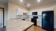 Located at 5000 Hutchison St in South Bloomfield, Ohio, this single-floor residence offers a thoughtfully designed layout with functional, modern finishes throughout. The kitchen is a standout feature, showcasing crisp white cabinetry, light granite countertops with an extended breakfast bar peninsula, and a full suite of black appliances including a refrigerator, electric range, built-in microwave, and dishwasher. Recessed lighting and durable wood-look flooring complete the kitchen's clean, contemporary look. The open-concept design connects the kitchen seamlessly to the living area, which features the same wood-look flooring and is bathed in natural light through a set of glass French doors that open to the outdoors. The bedrooms are carpeted for comfort and warmth, each with windows fitted with blinds that allow for natural light and outdoor views. The bathrooms are practical and well-finished — one features a tub/shower combination with grab bars and wood-look flooring, while the other includes a full vanity with a white cabinet, a tub/shower combo, and matching flooring. Neutral wall tones and consistent trim work carry throughout the entire space, contributing to a cohesive and move-in-ready atmosphere.