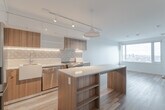 Located on the 25th floor at 55 Quebec Ave in Toronto's vibrant Junction neighbourhood, this one-bedroom, one-bathroom unit offers a thoughtfully designed layout across a single floor. The open-concept kitchen is a standout feature, showcasing two-tone cabinetry with warm wood-grain lower cabinets and crisp white upper cabinets, complemented by a decorative patterned tile backsplash and under-cabinet lighting. A large central island with a white quartz countertop provides additional workspace and storage, while stainless steel appliances, a farmhouse-style sink, and a statement pendant light complete the modern aesthetic. Light hardwood flooring flows throughout the space, enhancing its bright and airy feel. The bedroom is a calm retreat, featuring a wide picture window that frames expansive views of the Toronto skyline, filling the room with natural light. The bathroom is finished in clean white large-format tiles with a soaking tub and brushed gold fixtures, adding a refined touch. A private balcony, dedicated closet, and a functional hallway round out the unit. The overall design is contemporary and efficient, making excellent use of every square foot.