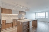 Located on the 25th floor at 55 Quebec Ave in Toronto's vibrant Junction neighbourhood, this one-bedroom, one-bathroom unit offers a thoughtfully designed layout across a single floor. The open-concept kitchen is a standout feature, showcasing two-tone cabinetry with warm wood-grain lower cabinets and crisp white upper cabinets, complemented by a decorative patterned tile backsplash and under-cabinet lighting. A large central island with a white quartz countertop provides additional workspace and storage, while stainless steel appliances, a farmhouse-style sink, and a statement pendant light complete the modern aesthetic. Light hardwood flooring flows throughout the space, enhancing its bright and airy feel. The bedroom is a calm retreat, featuring a wide picture window that frames expansive views of the Toronto skyline, filling the room with natural light. The bathroom is finished in clean white large-format tiles with a soaking tub and brushed gold fixtures, adding a refined touch. A private balcony, dedicated closet, and a functional hallway round out the unit. The overall design is contemporary and efficient, making excellent use of every square foot.